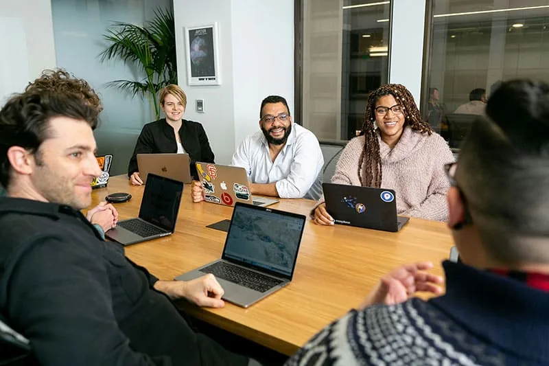 Team meeting around a conference table with laptops