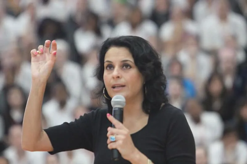 Jodee Blanco speaking into a microphone in front of a large audience