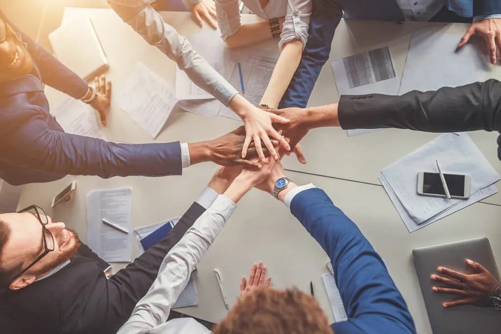 Team members joining hands over a meeting table