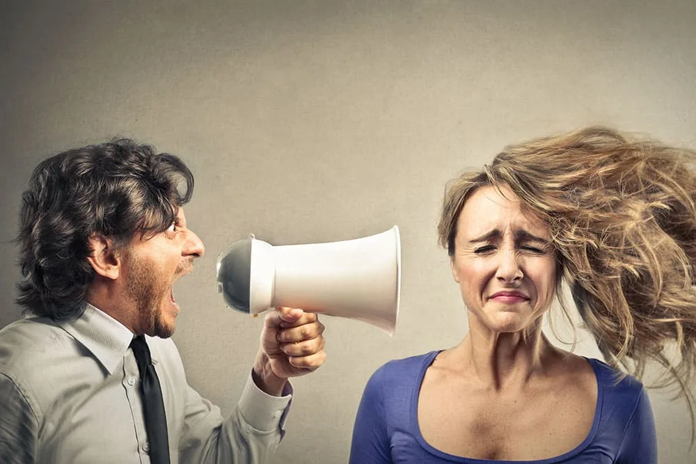 A man shouting through a megaphone at a startled woman